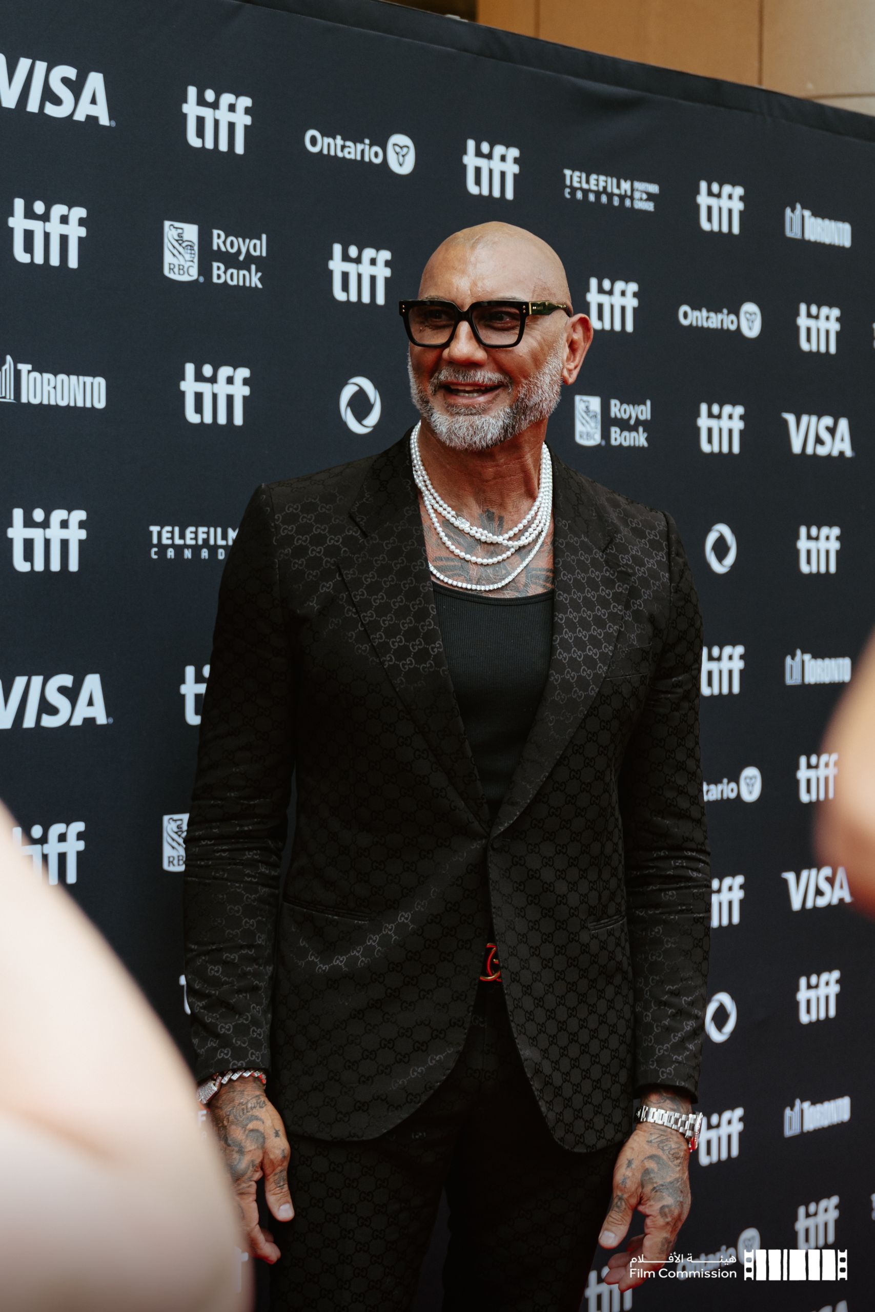 A7404372 Celebrity in black suit at TIFF red carpet step-and-repeat with Visa and Royal Bank sponsors — Toronto International Film Festival event photography by Origin Films