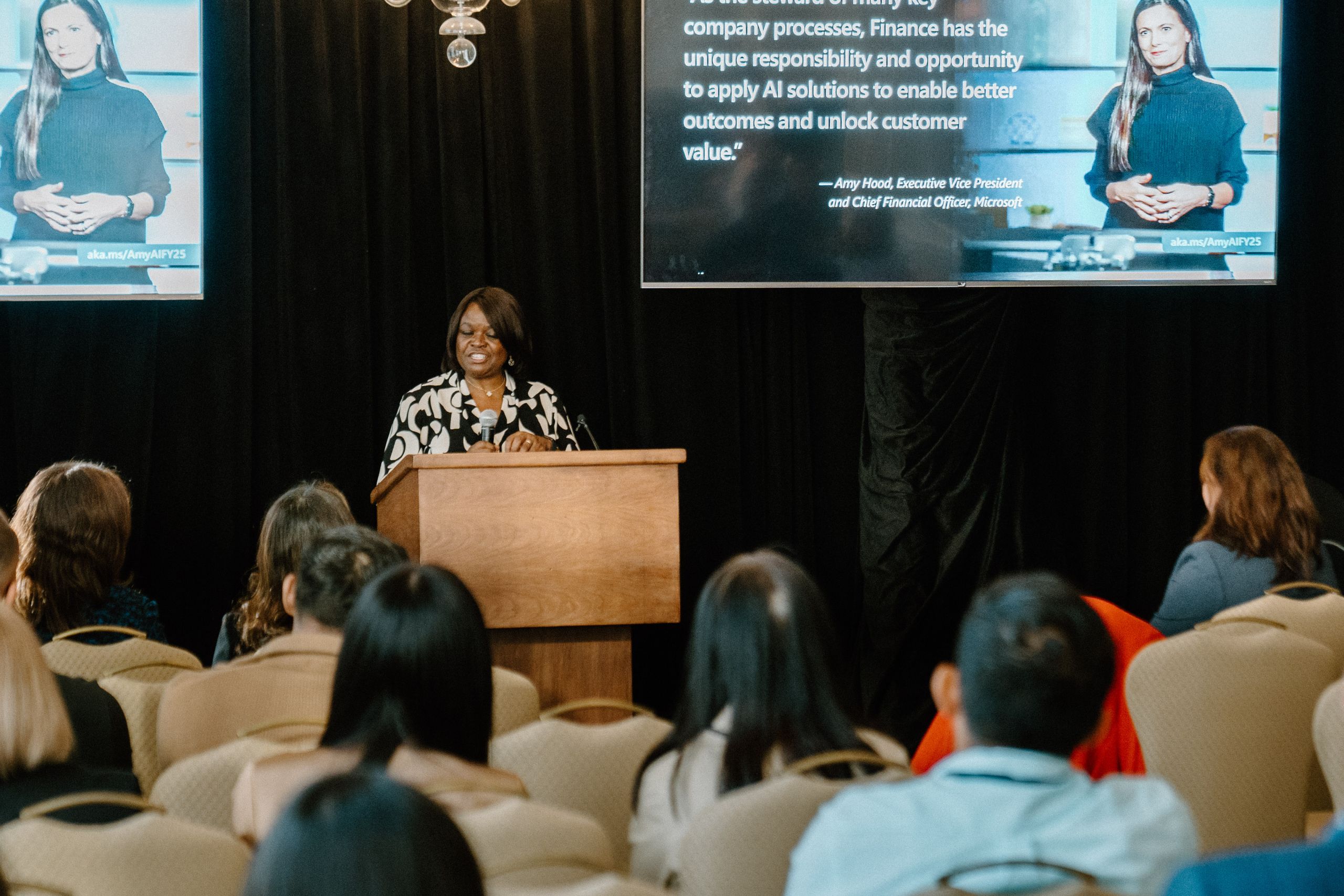 Corporate event speaker presenting at a Microsoft AI for Finance conference with Amy Hood CFO quote projected on screen photographed by Origin Films professional event photography
